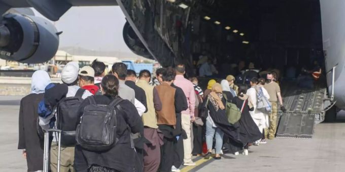 Menschen stehen auf dem Rollfeld und gehen an Bord eines US-Transportflugzeugs von Typ C-17 Globemaster III während ihrer Evakuierung am Hamid Karzai International Airport in Afghanistan. Foto: U.S. Marines/ZUMA Press Wire Service/dpa afghanistan