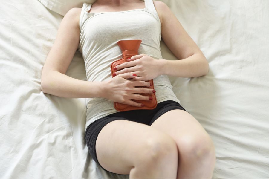 Frau mit Wärmflasche auf dem Bauch