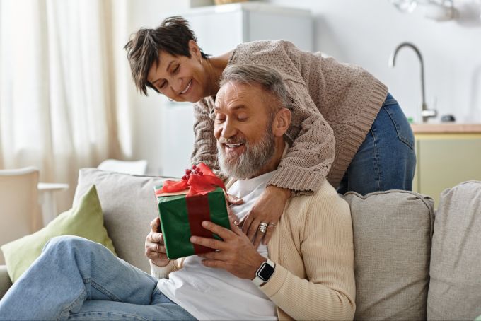 Auch Geschenke und kleine Aufmerksamkeiten im Alltag können ein Ausdruck der Liebe sein. Frau beschenkt ihren Mann
