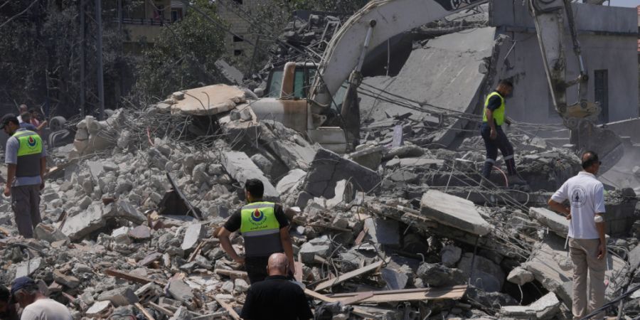 Menschen und Rettungskräfte versammeln sich vor einem zerstörten Haus, das von einem israelischen Luftangriff getroffen wurde. Foto: Mohammed Zaatari/AP/dpa