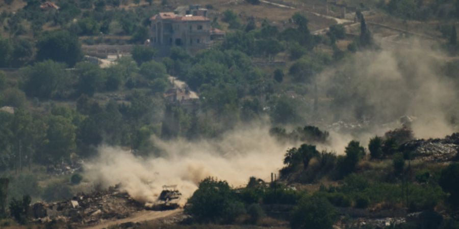 Ein israelischer Panzer fährt an zerstörten Gebäuden im Südlibanon vorbei, aufgenommen aus Nordisrael. Foto: Leo Correa/AP/dpa