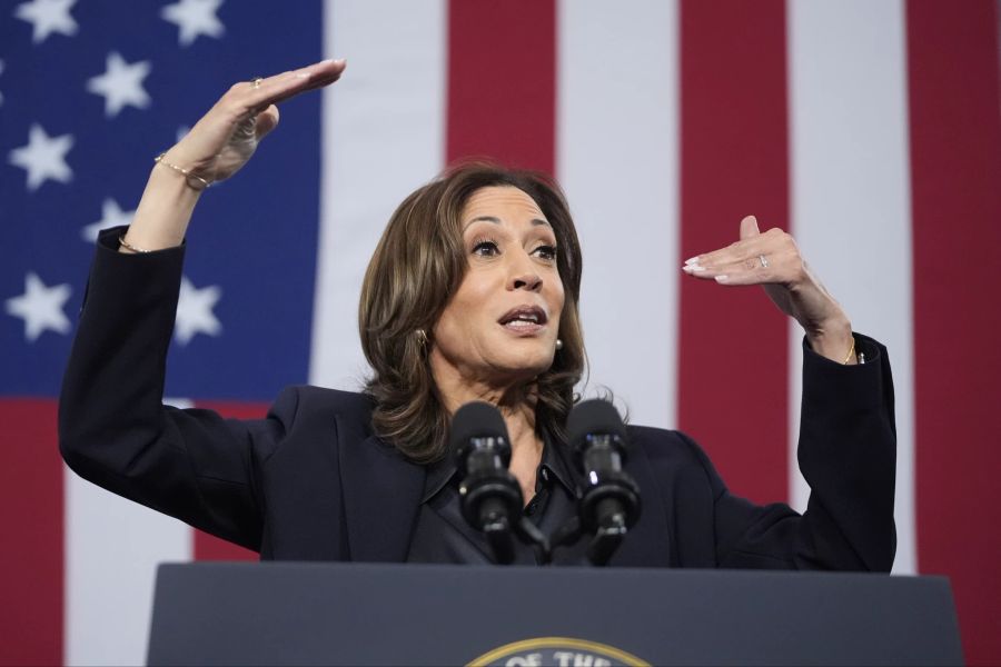 Kamala Harris gestikuliert vor Flagge