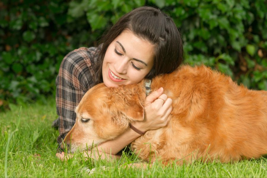 Frau mit Hund im Freien, kuschelnd