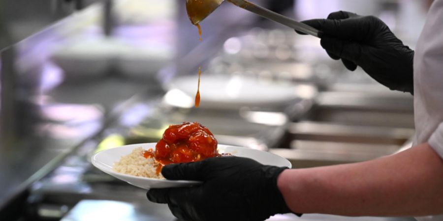 PRODUKTION - Eine Kantinenfrau gibt das Essen in der Mensaria der Johannes Gutenberg-Universität in Mainz aus. Foto: Jennifer Brückner/dpa/Archivbild