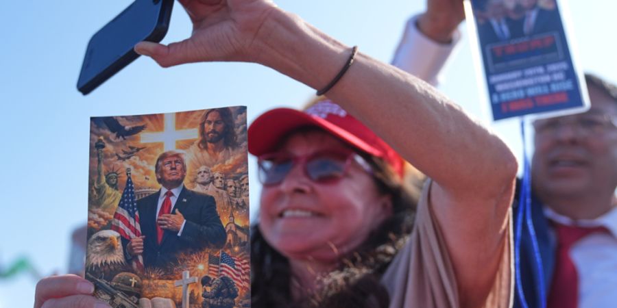 ARCHIV - Menschen hören US-Präsident Trump bei seiner Rede im Hafen von Corpus Christ, Texas, zu. Foto: Matt Rourke/AP/dpa