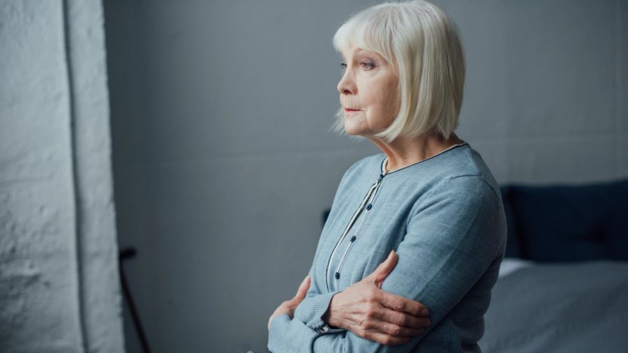 alte frau schaut aus fenster, grauer hintergrund