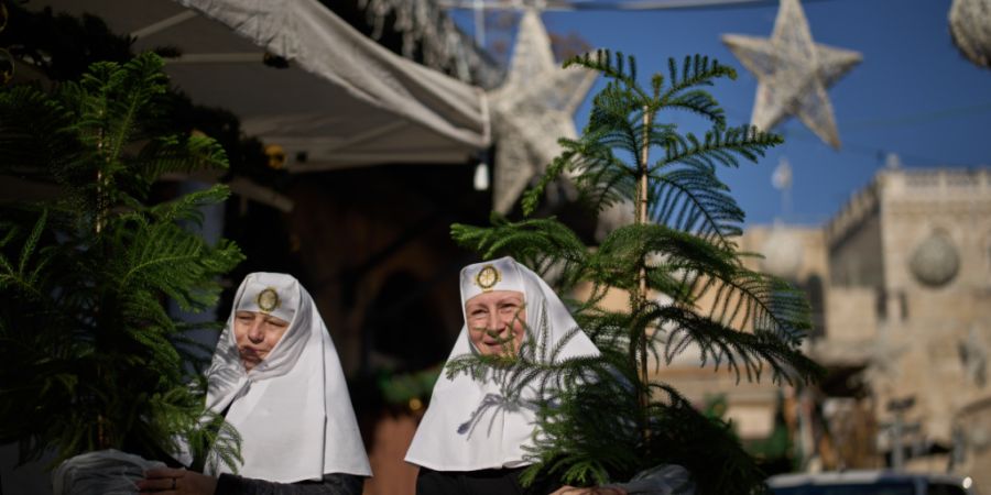 ARCHIV - Orthodoxe Christinnen tragen ihre Weihnachtsbäume vor dem Weihnachtsfest nach Hause. Foto: Leo Correa/AP/dpa