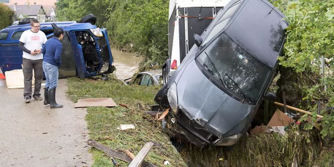 Einfach von den Fluten mitgerissen: Bewohner vor den Wracks der Autos im Val-de-Ruz. Es wurden beim Unwetter vier Personen verletzt. Unwetter vier