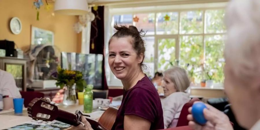 Julia Pohl (M), Musiktherapeutin, singt bei einer Gruppen-Musiktherapie-Stunde in einer betreuten Demenz-Wohngemeinschaft. Foto: Christoph Soeder/dpa