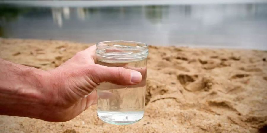 Ein Glas mit Wasser aus einem Baggersee. Foto: Rene Ruprecht/Illustration