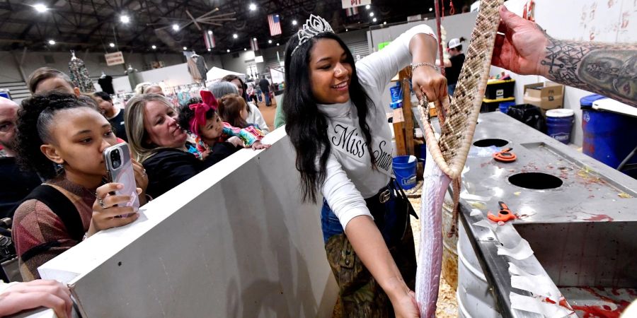 Trinity McGee, die Gewinnerin des Miss Snake Charmer-Wettbewerbs 2023, häutet eine Klapperschlange beim 65. World's Largest Rattlesnake Roundup in den USA.