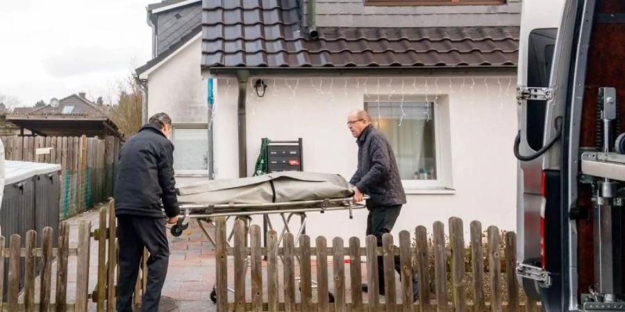 Bestatter bringen eine Trage mit einem Leichnam aus dem Wohnhaus in Glinde. Foto: Markus Scholz/dpa