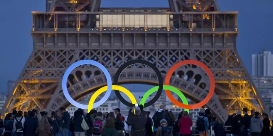 Die Olympischen Ringe leuchten am Fusse des Eiffelturms in Paris. Foto: Michel Euler/AP/dpa