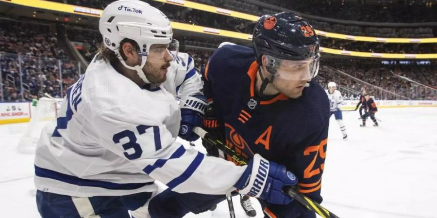 Timothy Liljegren (l,37) von Toronto in Aktion gegen Leon Draisaitl (29) von den Oilers. Foto: Jason Franson/The Canadian Press/AP/dpa