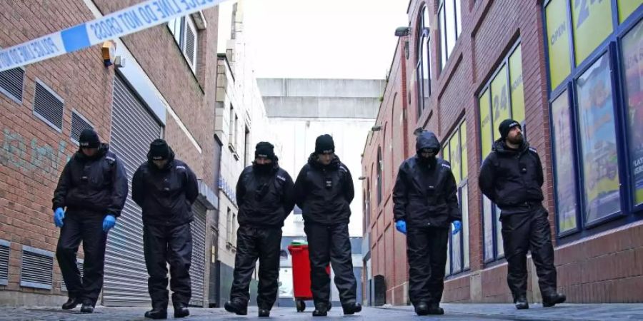 Polizisten führen eine Durchsuchung in der Nähe des Tatorts im Stadtzentrum durch, nachdem ein 12-jähriges Mädchen an den Folgen eines Angriffs gestorben ist. Foto: Peter Byrne/PA Wire/dpa