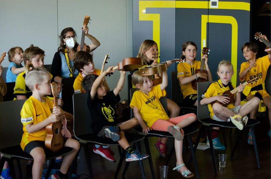 Grosse Freude bei den Kindern in Gelb und Schwarz während dem Musizieren.
