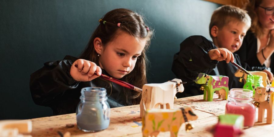 Kinder bemalen Holzkühe an der OHA