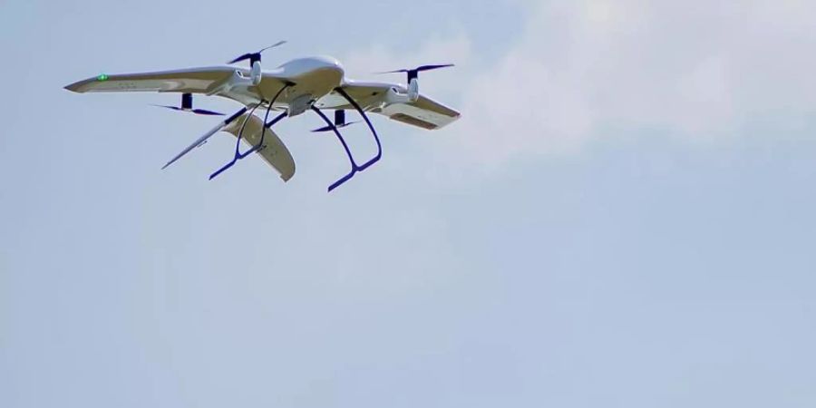 Eine Drohne des Start-Ups Wingcopter trägt ein Paket. Das mit Tragflächen ausgestattete Gerät kann senkrecht aufsteigen und dann auf der Strecke auch bei widrigen Wetterverhältnissen wie ein Propeller-Flugzeug fliegen. Foto: Wingcopter/dpa