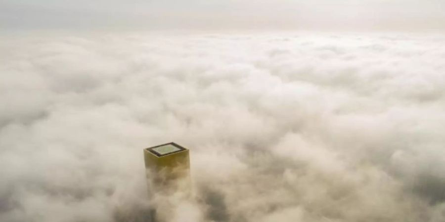 Ein Gebäude mit einem Hubschrauberlandeplatz ragt aus dem Smog über Pekings Innenstadt hervor. Foto: Xu Jingbo/SIPA Asia via ZUMA Wire/dpa