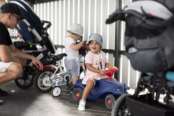 Kleinkinder beim Spielen mit einem Bobby Car und Fahrrad beaufsichtigt durch einen Betreuer beim Unterstand im Aussenbereich der Kita 6e der Stiftung GFZ, aufgenommen am 9. Juli 2020 in Zürich. Kita draussen Maskenpflicht