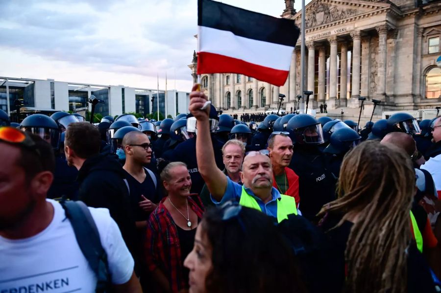 Teilnehmer einer Kundgebung gegen die Corona-Massnahmen stehen vor dem Reichstag.