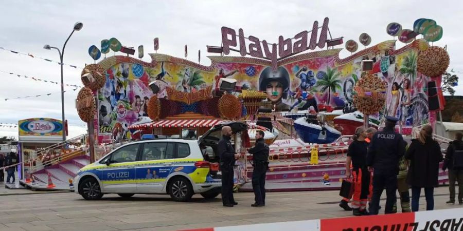 Polizisten und ein Polizeiwagen stehen vor dem Fahrgeschäft «Playball» beim «Potsdamer Oktoberfest». Foto: Julian Stähle/dpa-Zentralbild/dpa