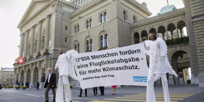 Aktivisten in Engelskostuem tragen ein Banner für die Petition «Ja zur Flugticketabgabe» vor das Bundeshaus. 17'858 Menschen forderten die Einführung einer Flugticketabgabe. Flugticketabgabe