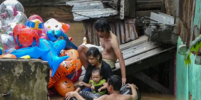Familie in Jakarta auf der Flucht vor den Wassermassen Familie in Jakarta auf der Flucht vor den Wassermassen