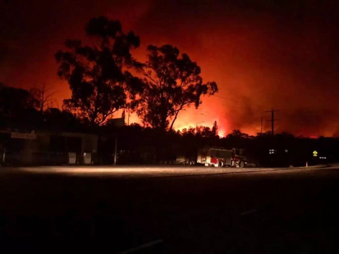 Flammen färben den Himmel bei einem Buschfeuer in der Nähe des Nowa Nowa Generalstores in Nowa Nowa, East Gippsland, rot. buschbrände australien