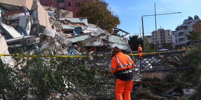 Rettungskräfte stehen vor einem eingestürzten Gebäude. Erdbeben Albanien