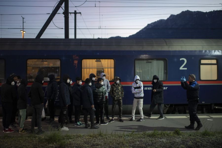 Grenzwächter bringen Flüchtlinge aus einem Zug aus Wien zur Kontrolle, am Freitag, 19. November 2021, am Bahnhof in Buchs.