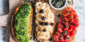 Drei belegte Brote, jeweils mit Avokado, Banane oder Tomate.