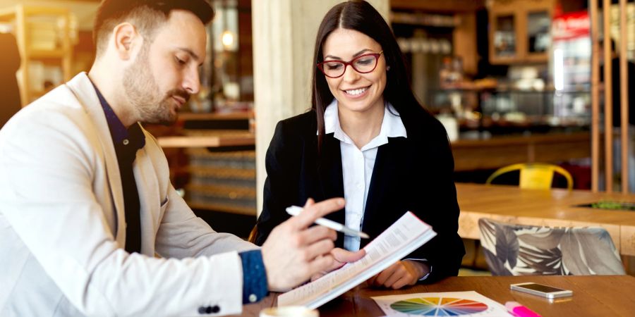 Man mit Block und Stift sitzt mit einer Frau an einem Tisch.