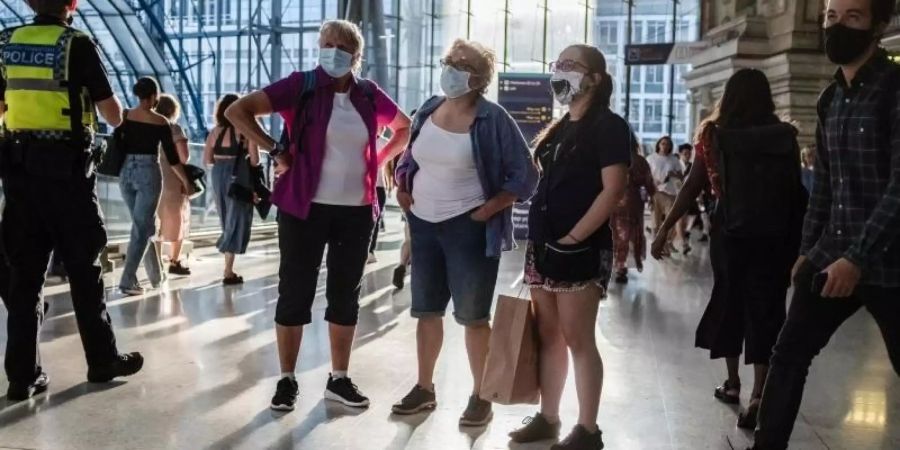 Menschen mit Mund-Nasen-Schutz stehen in einer U-Bahn Station in London. Foto: May James/SOPA Images via ZUMA Press Wire/dpa