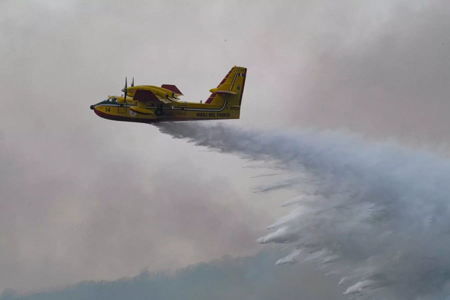 Ein Löschflugzeug schüttet Wasser über den Bränden aus.