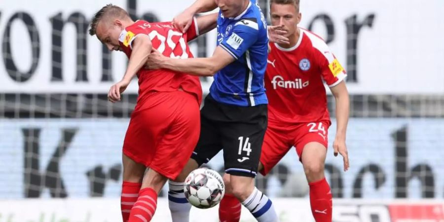 Bielefelds Joan Simun Edmundsson (M) versucht sich gegen zwei Kieler durchzusetzen. Foto: Friso Gentsch