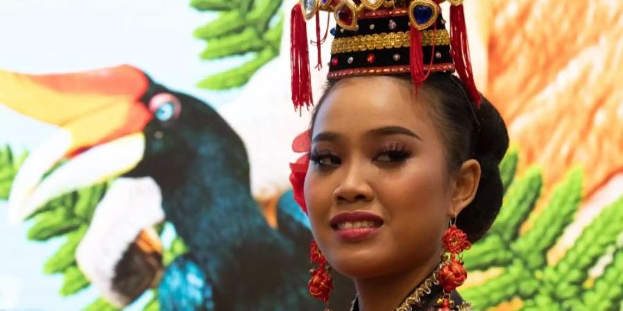 Eine Frau mit einem traditionellen malaysischen Kopfschmuck beobachtet die Eröffnung der Reisemesse ITB auf dem Messegelände in Berlin. Malaysia ist das Partnerland der 53. ITB. Foto: Ralf Hirschberger