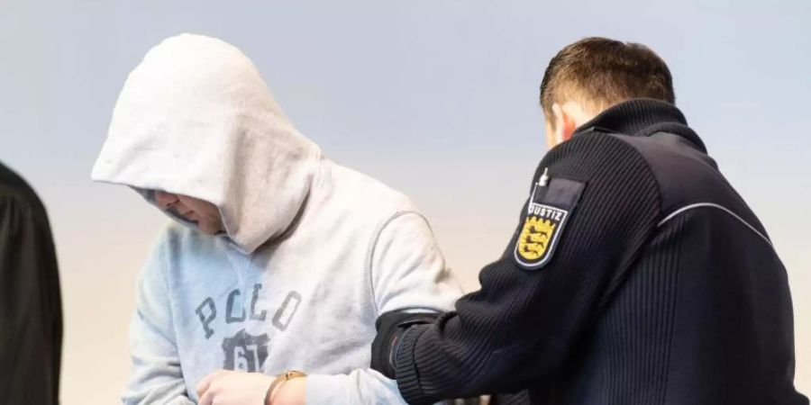 Der Angeklagte wird von einem Justizbeamte in den Sitzungssaal des Landgerichts gebracht. Foto: Patrick Seeger/dpa