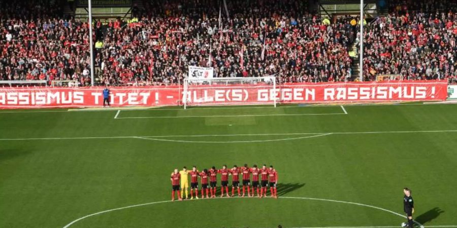 Die Spieler vom SC Freiburg und Fortuna Düsseldorf gedenken in einer Schweigeminute den Opfern der Gewalttat von Hanau. Foto: Patrick Seeger/dpa