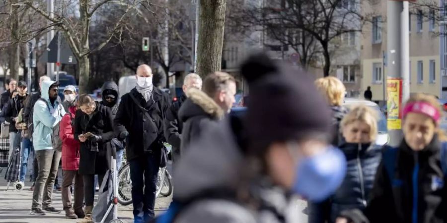 Zahlreiche Menschen stehen in Berlin vor einem Supermarkt Schlange. Foto: Christoph Soeder/dpa