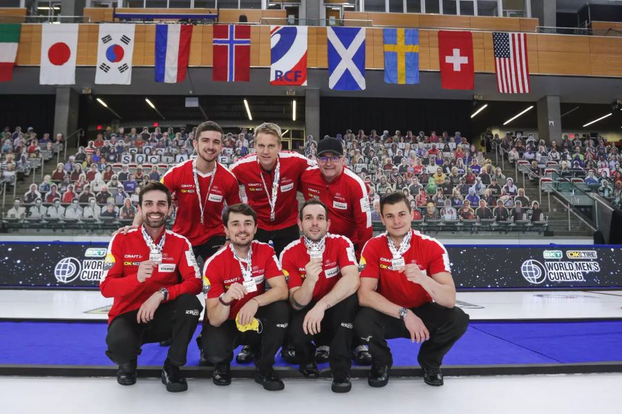 Die Schweizer Curling-Delegation zeigt stolz ihre WM-Bronzemedaille.