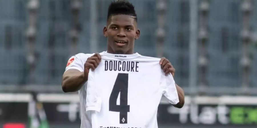 Mönchengladbachs Breel Embolo hält nach seinem Tor zum 1:0 ein Trikot von Mamadou Doucoure hoch. Foto: Bernd Thissen/dpa