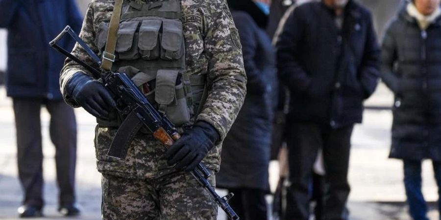 Ein kasachischer Soldat patrouilliert in Almaty nahe einer Polizeistation. Hinter ihm versammeln sich Angehörige von Personen, die nach den Protesten gegen die Regierung verhaftet wurden. Foto: Sergei Grits/AP/dpa