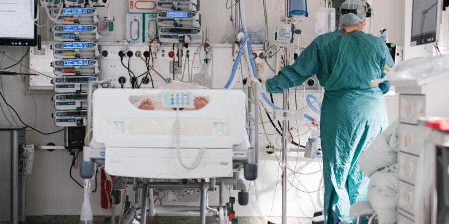 Eine Intensivpflegerin versorgt auf der Intensivstation einen an Covid-19 erkrankten Patienten. Foto: Ole Spata/dpa