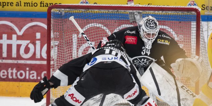 Lugano's player Alessio Bertaggia, Lugano's goalkeeper Niklas Schlegel and Bern's player Philip Varone, from left, fight for the puck, during the preliminary round game of National League Swiss Championship between HC Lugano and SC Bern, on Saturday, 22 January 2022, at the at the ice stadium Corner Arena in Lugano. (KEYSTONE/Ti-Press/Pablo Gianinazzi) HOCKEY: HC LUGANO - SC BERN