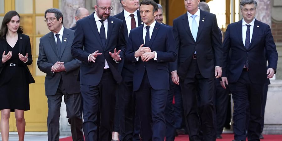 Emmanuel Macron (M), Präsident von Frankreich, spricht mit Charles Michel (Mitte l), Präsident des Europäischen Rates, auf dem Weg zu einem Gruppenfoto während eines informellen Gipfels der EU-Staats- und Regierungschefs im Schloss von Versailles. Foto: Michel Euler/AP/dpa