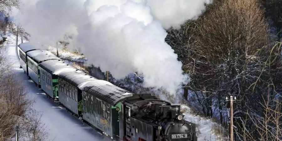Die Fichtelbergbahn schnauft durch den Winterwald im Erzgebirge. Foto: Jan Woitas/dpa-Zentralbild/dpa