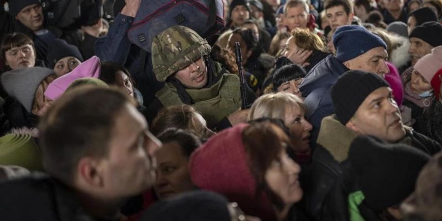 Ein ukrainischer Soldat versucht, die Menschenmenge aufzulösen, die am Bahnhof von Kiew in einen Zug nach Lwiw steigen will. Foto: Emilio Morenatti/AP/dpa