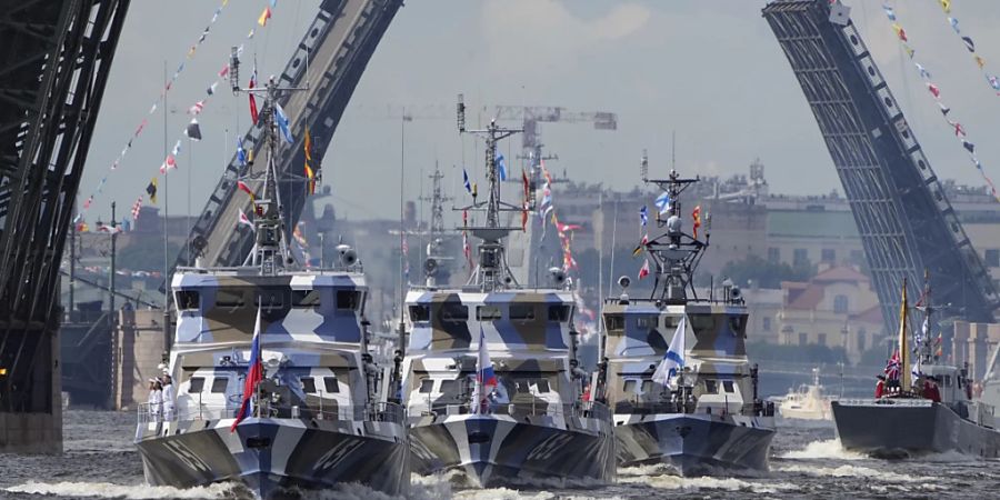 Kriegsschiffe fahren auf der Newa an hochgezogenen Zugbrücken vorbei im Rahmen einer Probe für die Marineparade zum Tage der Marine in Russland. Foto: Dmitri Lovetsky/AP/dpa