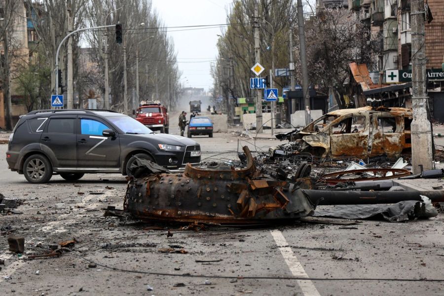 Ein Teil eines zerstörten Panzers und ein verbranntes Fahrzeug auf einer Strasse in Mariupol.